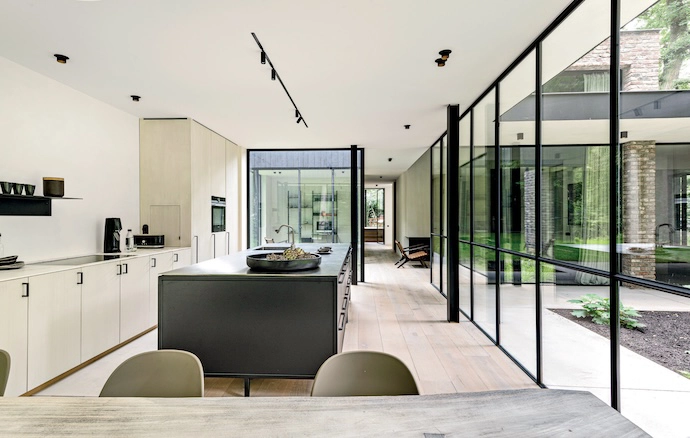 Visible through the glass “walls” of the lounge, the black VIPP kitchen’s modular design combines painted MDF panels with Sahara Blanc marble countertops. The dining table and Harbour chairs are by Moka Tales.
