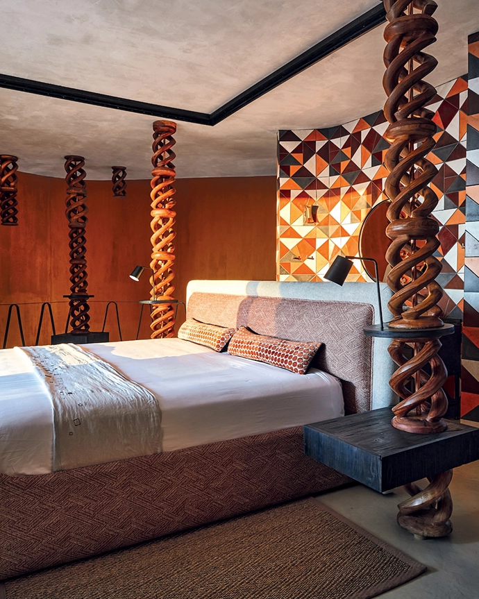 Interior designer Melanie Redecker created totems from hand-carved African stools. The Namibian-made bespoke bed complements the curve of the walls.