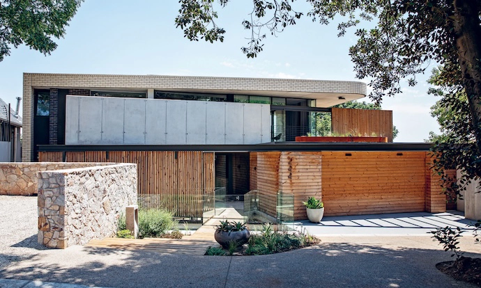 From the street, the house reveals a series of angular, fragmented planes in brick, timber and concrete.