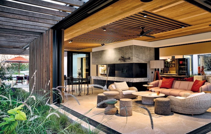 The indoor-outdoor braai patio features a sofa by Patricia Urquiola for Kettal from Marlanteak, a coffee table from Lemon Furniture, Weylandts armchairs, and cork stools by Wiid Design.