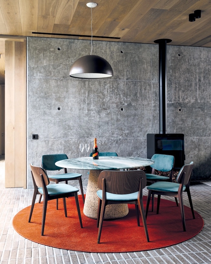 In the wine cellar, a cork-and-marble table by Laurie Wiid and Kartell chairs from True Design create another entertainment space next to the Fire and Gas Lifestyles fireplace.