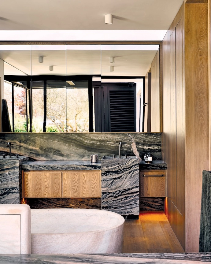 The main bathroom opens onto the same private terrace as the main bedroom. Wooden floors are a warm contrast against the dramatic Afristone slabs in the shower and on the vanity. The stone bathtub is by Bone Studio, and the fixtures are from Lavo Bathroom Concepts.