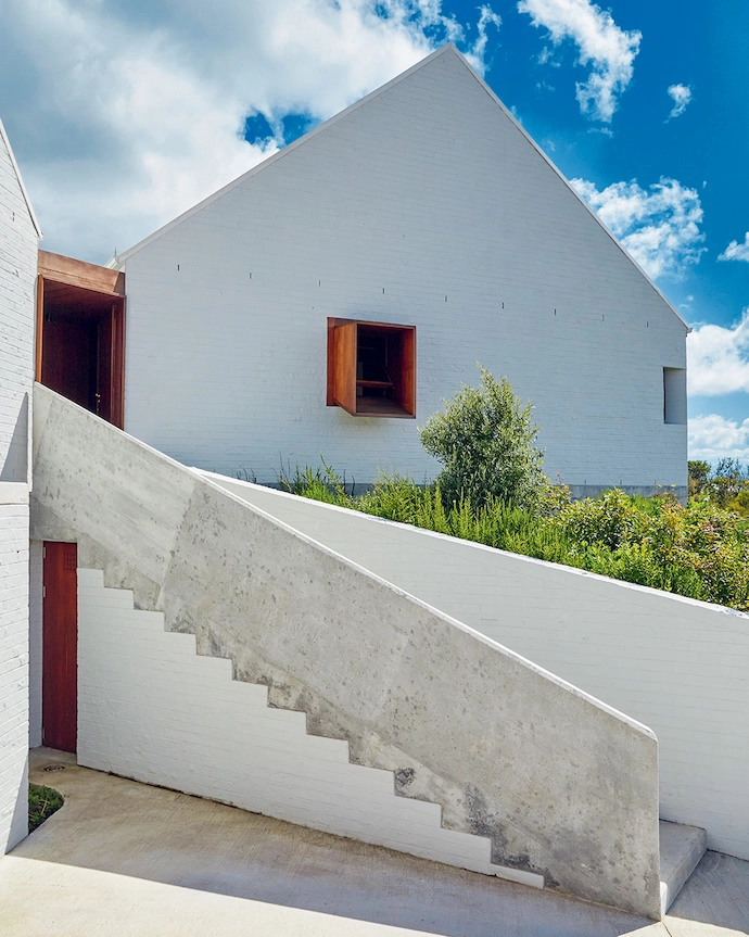 A sculptural stairway leads from the road and garage level up to the front door.