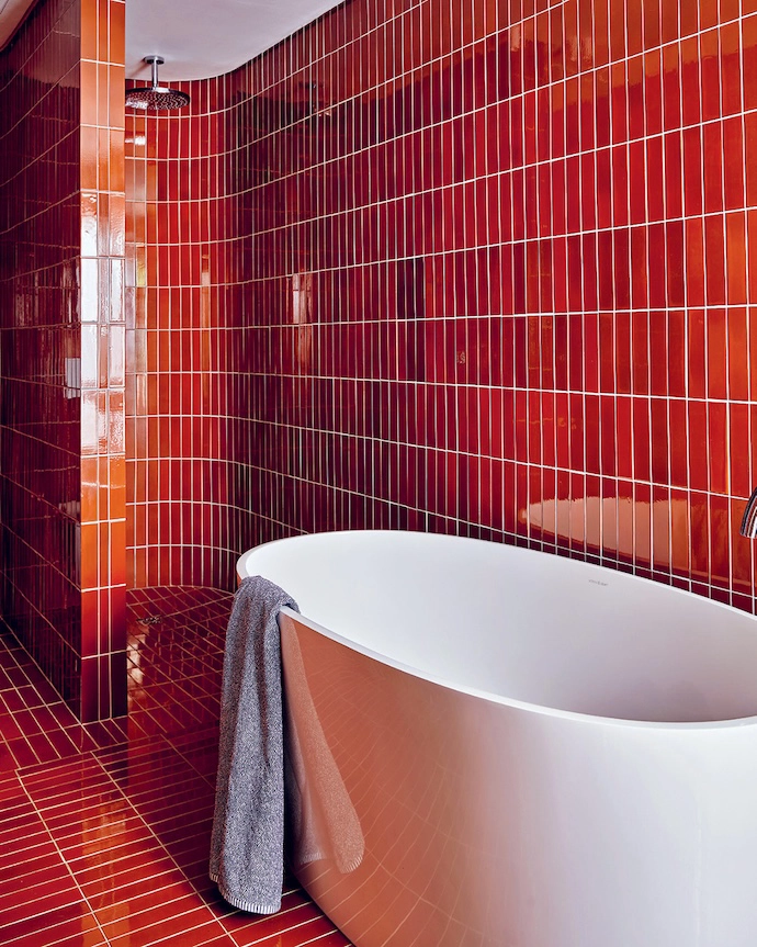 The main bathroom features floor-to-ceiling Kalki Ceramics tiles and a bathtub by Victoria + Albert.