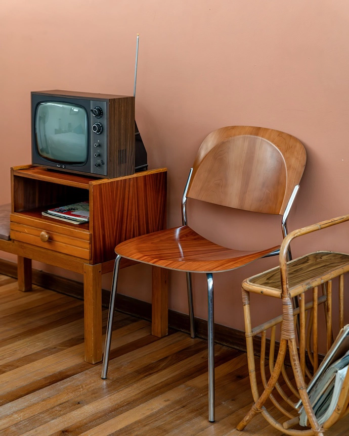 A terrestrial TV set, wicker magazine rack and Stylex wood veneer chair evoke analogue times.