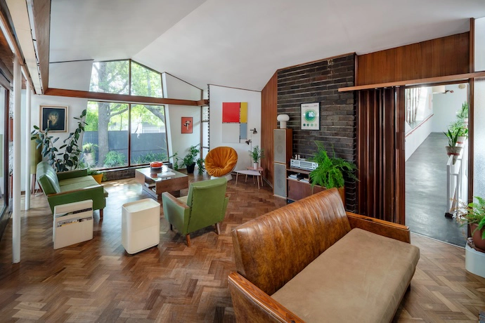 Another APS Conradie design signature is floor-to-ceiling glazing, here illuminating the open-plan living room and its contents, including a Kartell Model 4675 magazine rack by Giotto Stoppino, a storage unit by Anna Castelli (also for Kartell), an orange papasan chair, and a print of Theo van Doesburg’s Principles of Neo-Plastic Art .