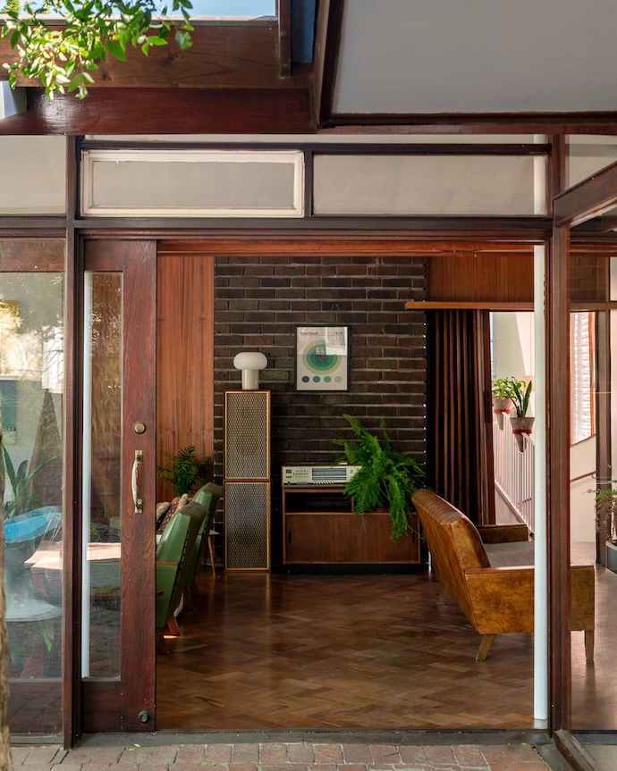 The open-plan living area contrasts a rosewood parquet with face brick and wood finishes.