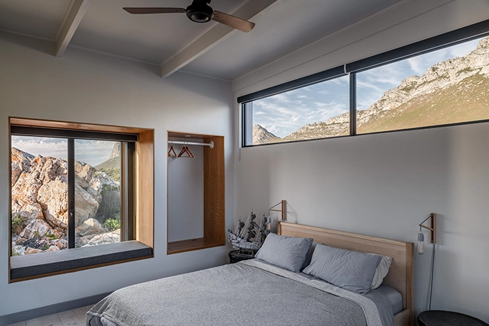 Featuring an open wall-recessed cupboard designed by the owner, this bedroom with its mountain views, and another, with sea views, is connected to a shared bathroom.
