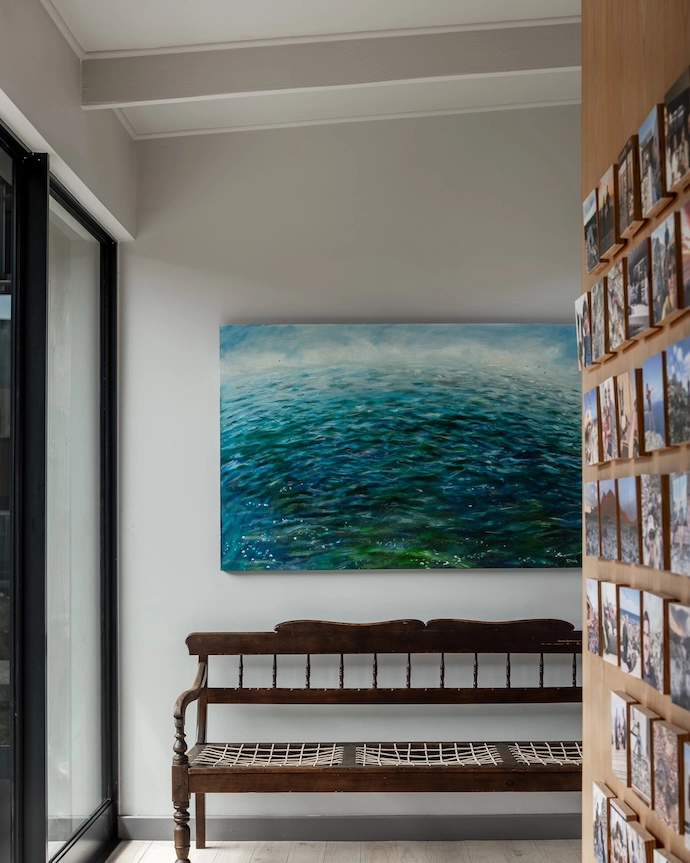 The entrance lobby, a windless retreat, come rain or shine; the entrance lobby, featuring a family photo wall, riempiesbank heirloom, and painting by Isabelle Webb.