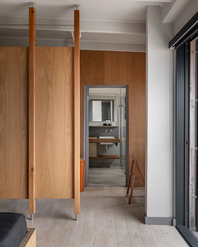 Designed by the owner and built by her father, a wooden partition demarcates space for a home office in the en suite bedroom.