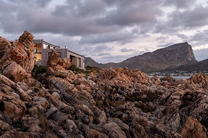 Designed to recede into its surroundings, the residence is clad in locally sourced cypress wood, which has naturally weathered to grey. To allow for the free movement of wildlife, the house is anchored to the rocks with elevated point loads.