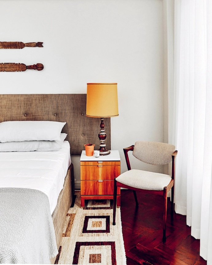 A lamp – a family heirloom – fashioned with an orange silk shade sits on a walnut bedside table.