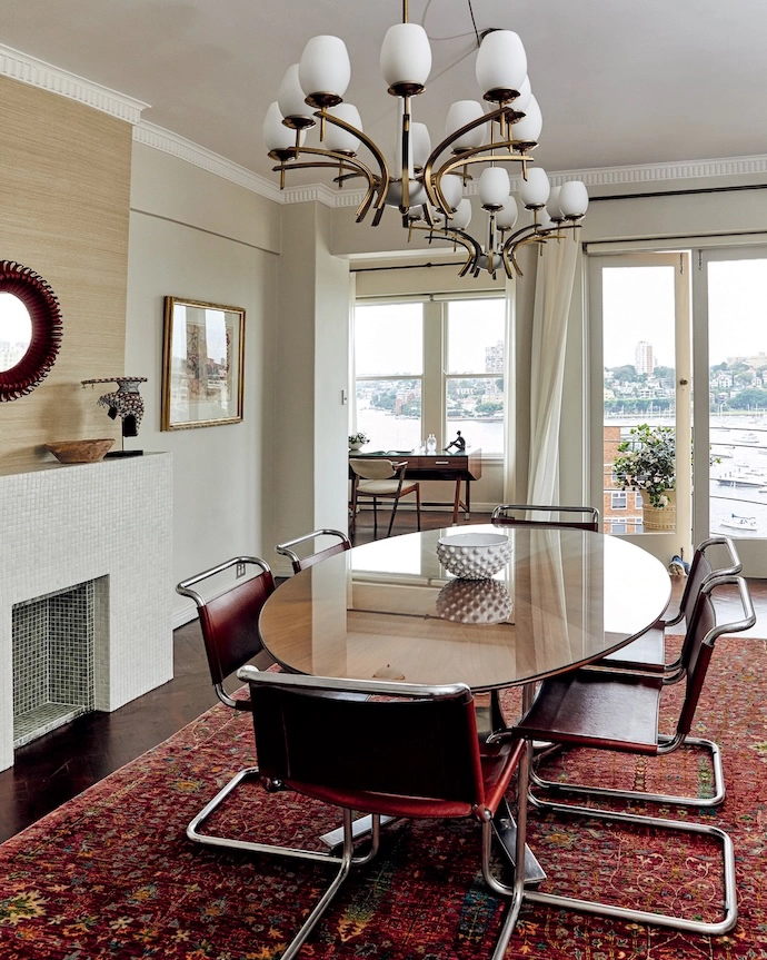 Beneath a pair of Mid-century brass-and-glass chandeliers, a walnut and sculpted-steel dining table by Osvaldo Borsani is surrounded by vintage Spanish chrome-and-leather chairs.