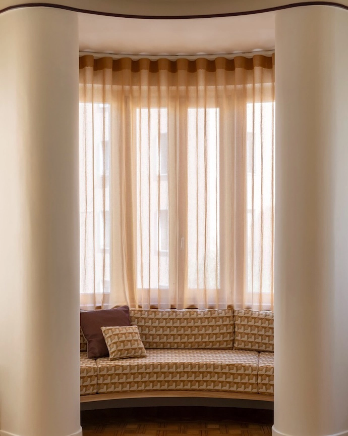 The living room nook with original parquet flooring featuring curtains in FISCHBACHER fabric 113/117/132; and custom bench in Relief Cammello fabric by l’Opificio.