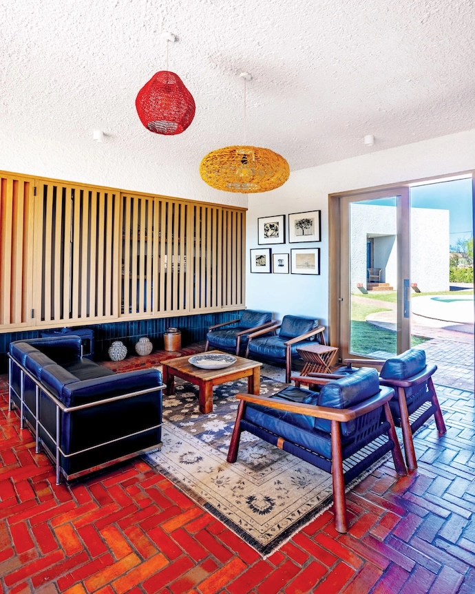 The living area in the cottage features Magnet armchairs by John Vogel and a replica of Le Corbusier’s “Le Cube” sofa. More tree-inspired art adorns the far wall, including work by (clockwise from top left) David Botha, William Kentridge, Pierneef, Heinz Modler and Walter Battiss.