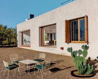 The southeastern facade of the house with views over the Karoo landscape. Protruding from the wall, you can see one of the exterior waterspouts designed by the architects. The walls thicken at specific points, allowing for hidden rainwater downpipes and other services.