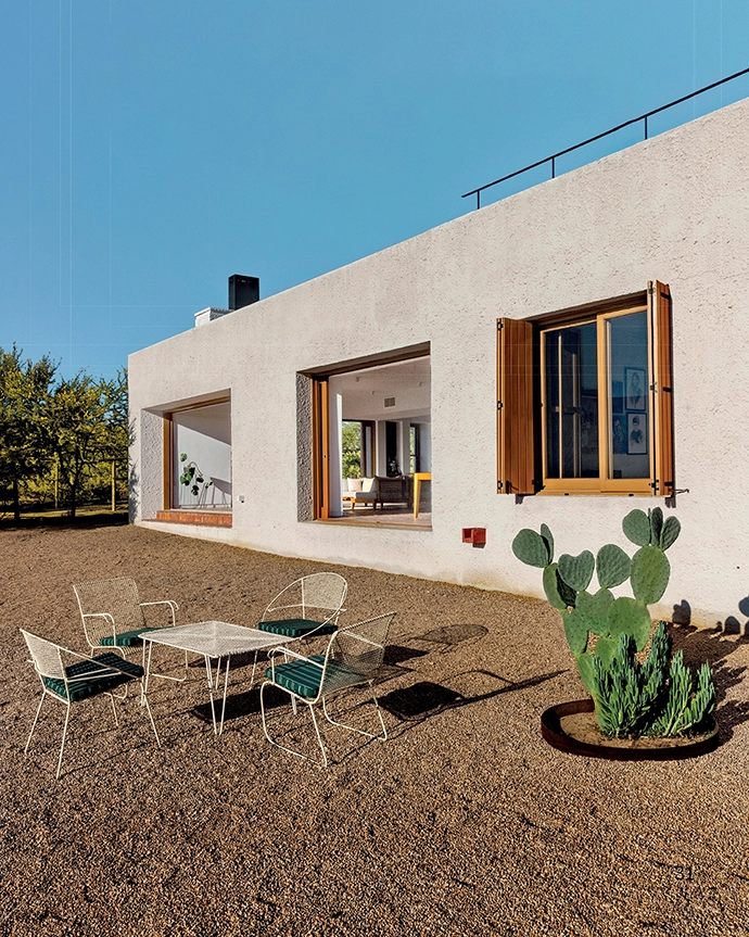 The southeastern facade of the house with views over the Karoo landscape.  Protruding from the wall, you can see one of the exterior waterspouts designed by the architects. The walls thicken at specific points, allowing for hidden rainwater downpipes and other services.