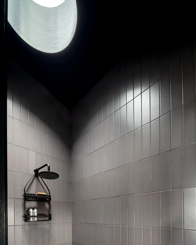 Making a nod to the nautical, the submarine-grey bathroom south- and east-facing sliding doors that encourage cross-ventilation. Making a nod to the nautical, the submarine-grey bathroom is fitted with a porthole window, circular skylights and a round mirror to maximise natural light.