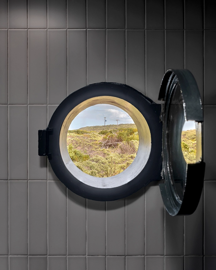 Making a nod to the nautical, the submarine-grey bathroom south- and east-facing sliding doors that encourage cross-ventilation. Making a nod to the nautical, the submarine-grey bathroom is fitted with a porthole window, circular skylights and a round mirror to maximise natural light.