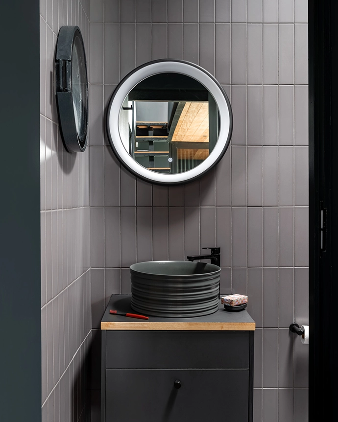 Making a nod to the nautical, the submarine-grey bathroom south- and east-facing sliding doors that encourage cross-ventilation. Making a nod to the nautical, the submarine-grey bathroom is fitted with a porthole window, circular skylights and a round mirror to maximise natural light.