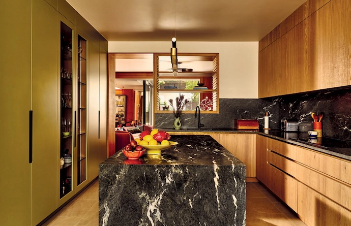 At Palace Gardens residential project in Notting Hill, London, warm terracotta hues and sage-green contrasts dominate the palette – in the entryway, the lounge anchored by a curved sofa, the dining area with its textured wallpaper, and the deep-red marbled wallpaper that’s been used in the guest bathroom. The kitchen continues the earthy aesthetic with luxe stone surfaces.