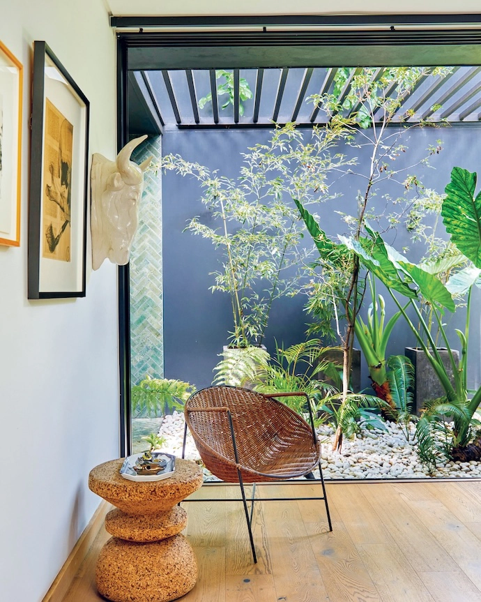 Another planted courtyard provides natural light and ventilation in the main bedroom – and a space for an outdoor shower. The wicker chair is a vintage piece, and the cork stool is by Wiid Design.