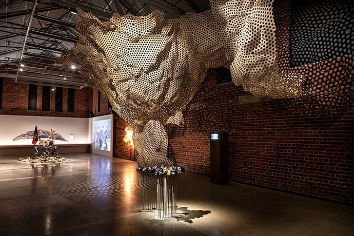 View of Reverse Futures exhibition showing Cave_bureau’s installation Shimoni Slave Cave (2022–2023) with the model of the cave visible in the foreground; and Georgia Munnik, The Strangling Fruit (2026) and Paula Gaetano Adi, Guanaquerx (2024)