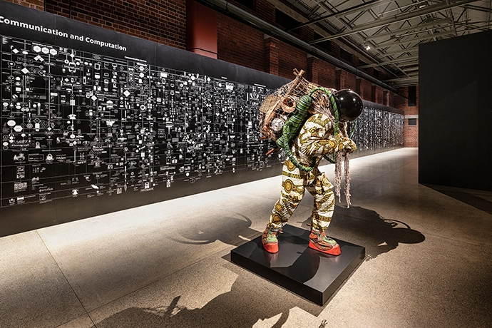 Yinka Shonibare, Refugee Astronaut X (2024), and in the background,
Calculating Empires: A Genealogy of Technology and Power since
1500 (2023) by Kate Crawford and Vladan Joler, in the Reverse Futures
exhibition.