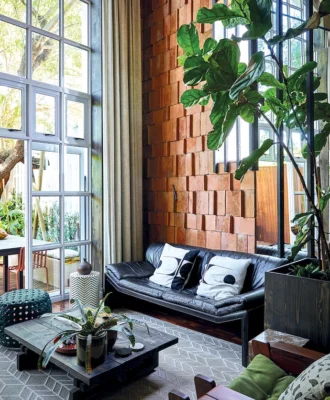 The terracotta roof tiles on the wall catch light across their uneven surfaces, giving the tall room a warmth that paint or plaster can’t match.