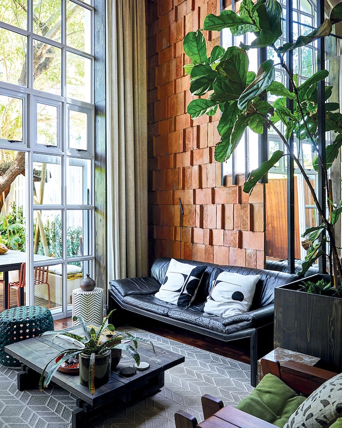 The terracotta roof tiles on the wall catch light across their uneven surfaces, giving the tall room a warmth that paint or plaster can’t match.