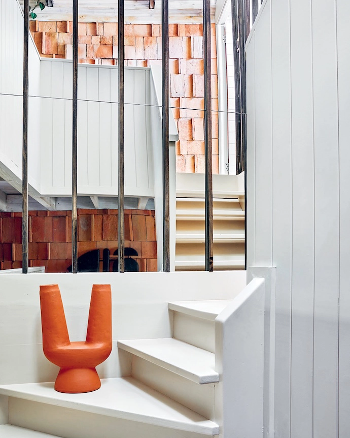 The staircase pulls the eye upwards, carrying the geometry of the ground floor into the mezzanine.