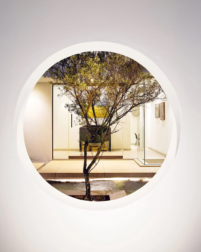 A quirky porthole in the perimeter wall allows curious passers-by to catch a glimpse of the architectural journey unfolding inside.