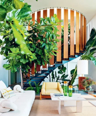 Plants integrated into the living room decor subtly interact with the elegant spiral staircase that leads to the main suite. A Tuft y-Time sofa by Patricia Urquiola for B&B Italia is complemented by coffee tables in Moleanos limestone from the Alma de Comporta collection by the home’s architect Christophe Bernard.