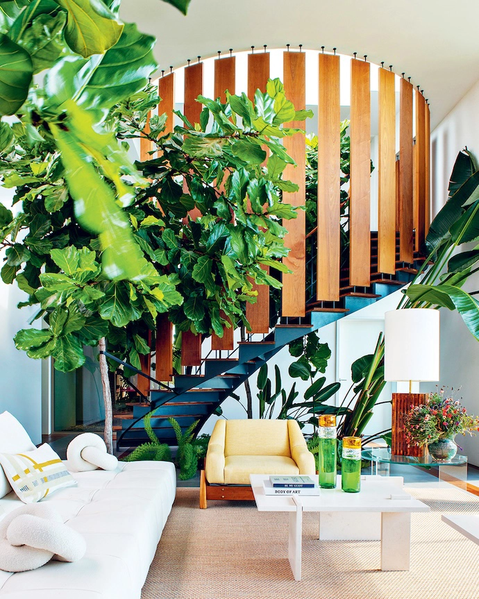 Plants integrated into the living room decor subtly interact with the elegant spiral staircase that leads to the main suite. A Tuft y-Time sofa by Patricia Urquiola for B&B Italia is complemented by coffee tables in Moleanos limestone from the Alma de Comporta collection by the home’s architect Christophe Bernard.