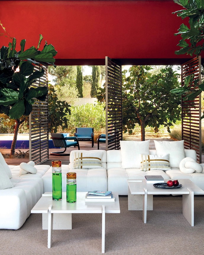 The patio and its water feature reveal themselves through large pivoting panels of slatted wood, extending the living space to the outdoors.