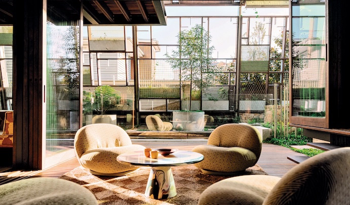  On a semi-outdoor deck, four GUBI Pacha lounge chairs surround an upcycled plastic Meltingpot table by Dirk van der Kooij.