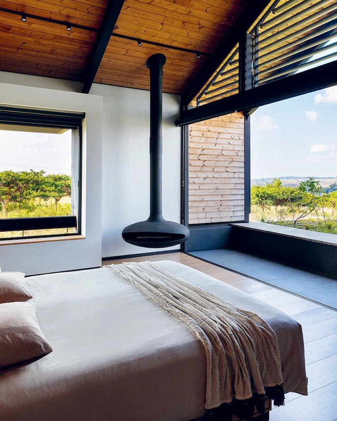 The main bedroom looks out over the greenbelt and the natural veld stretching to the horizon. An Aero suspended fireplace warms the room.