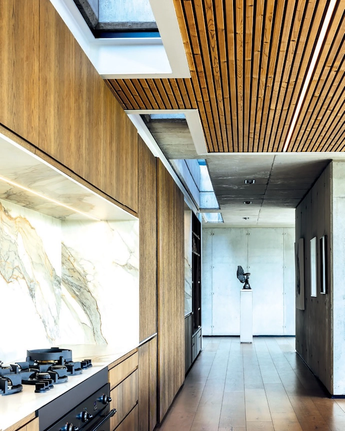 Natural light pours in from a narrow strip of skylights above the kitchen and living space.