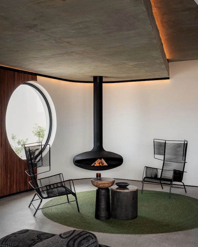 A pair of Fifty armchairs by Ligne Roset near an Aero suspended fireplace off er views through a porthole window.
